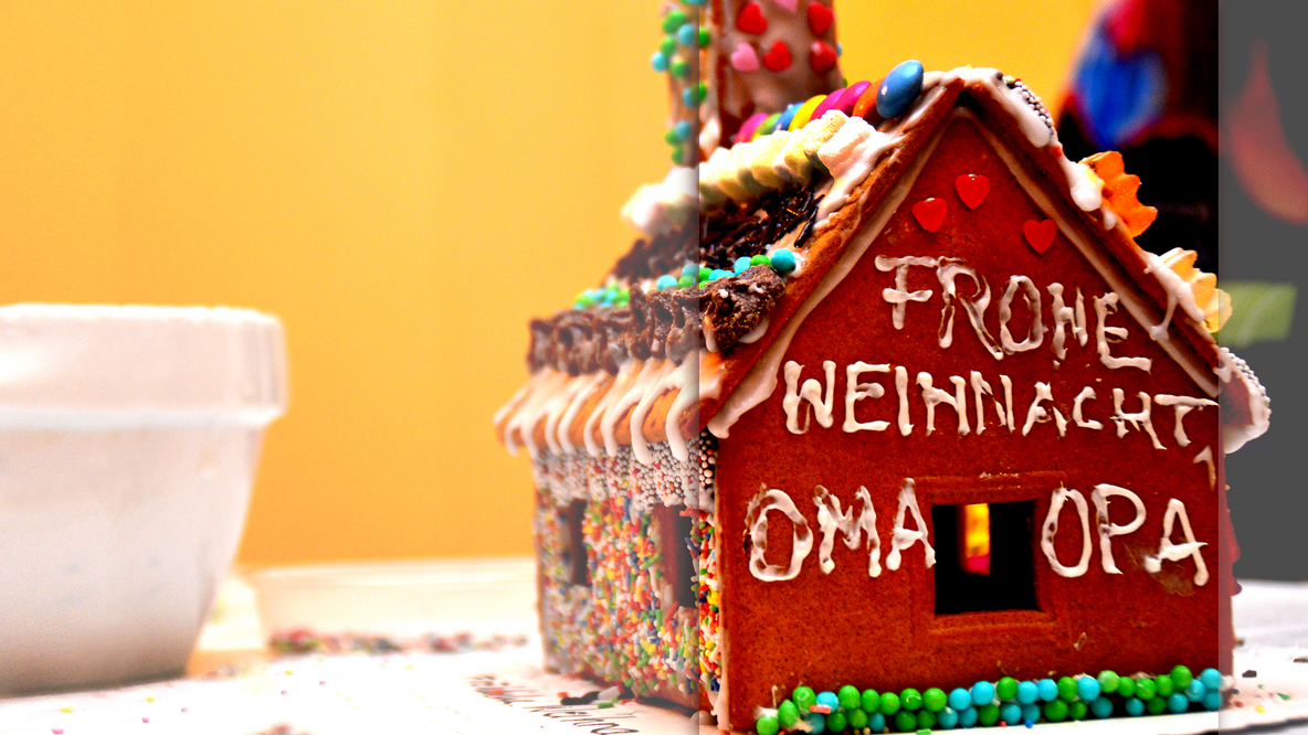 Foto: Ein verziertes Lebkuchen-Knusperhaus, auf dem in Zuckerguss "Frohe Weihnachten, Oma und Opa" steht
