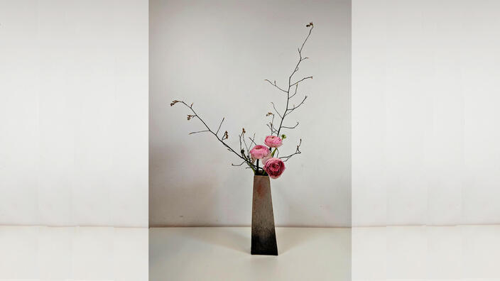 Foto: Ein Ikebana-Arrangement mit Rosen vor weißer Betonwand